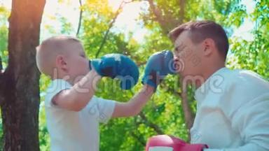 父亲和儿子戴着拳击手套在房子附近的草坪上<strong>打拳</strong>击